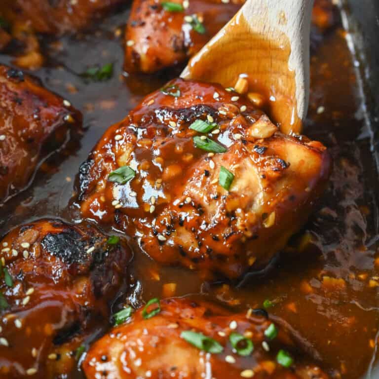 A spoon scooping up a piece of chicken in the slow cooker.