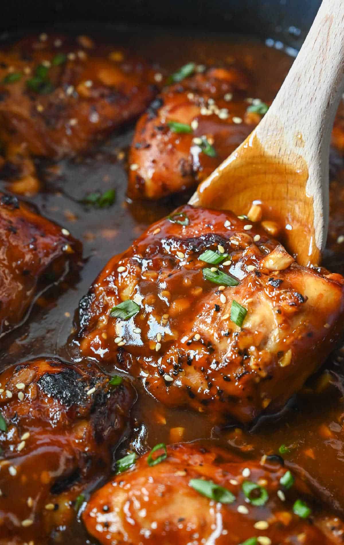 A spoon scooping up a piece of chicken in the slow cooker.