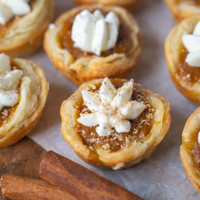 Mini pumpkin pie bites on a platter with cinnamon sticks.