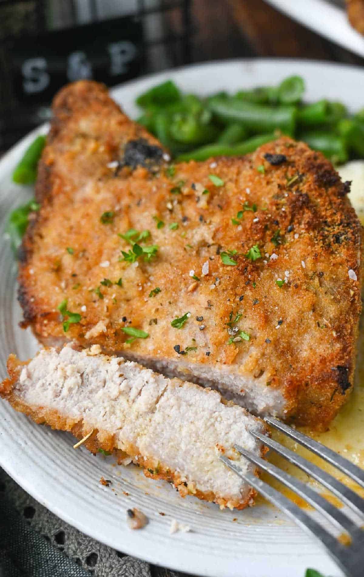 Oven fried pork chop with a slice out of it.