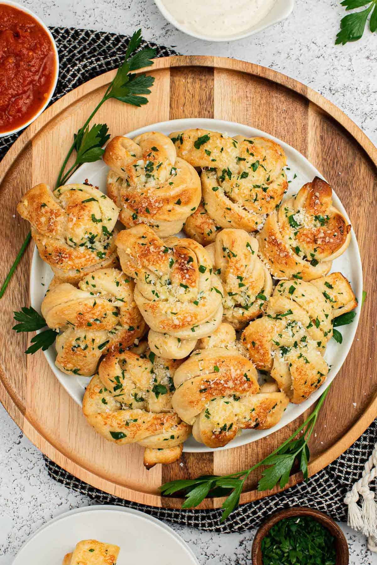 A plate of garlic knots with a side of marinara sauce.