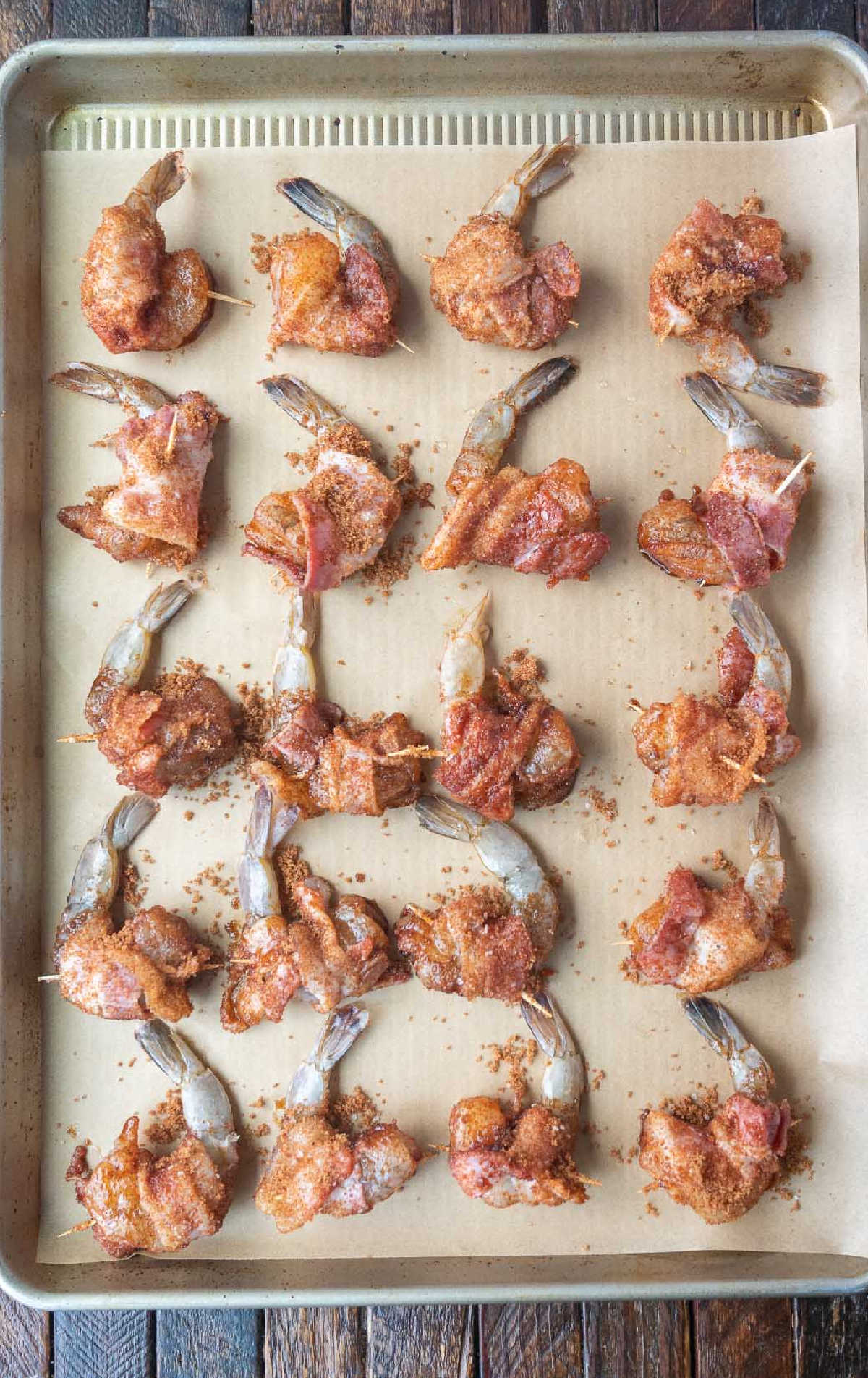 Bacon wrapped shrimp placed on a baking sheet.