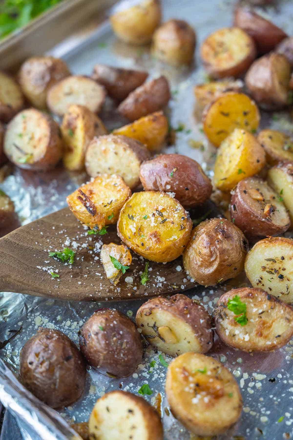 A wooden spatula scooping up some baby potatoes.