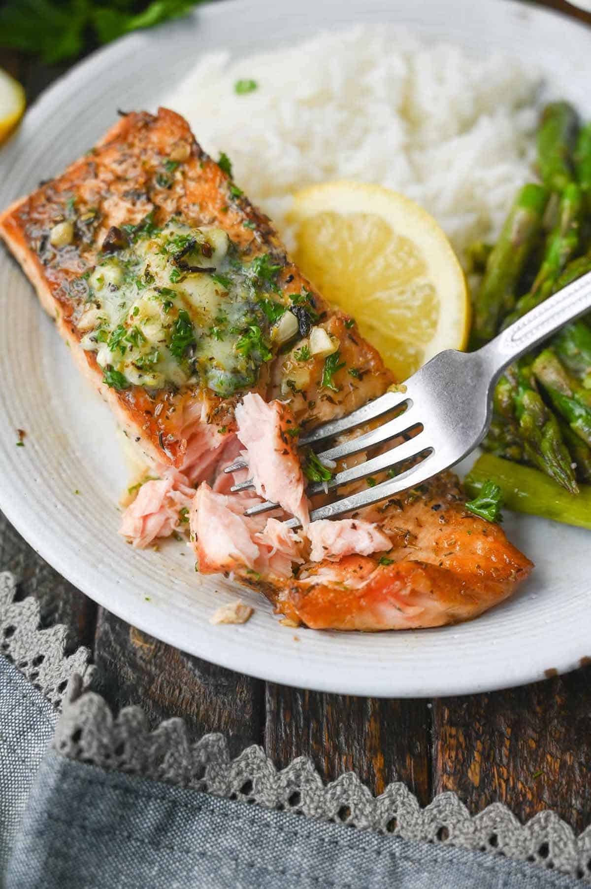 Salmon filet placed on a plate with rice and asparagus.