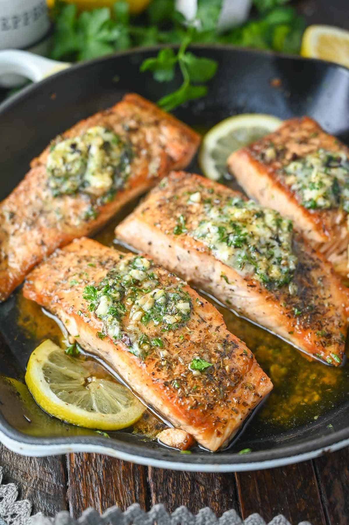 Salmon filets cooked in a skillet and lemon slices.