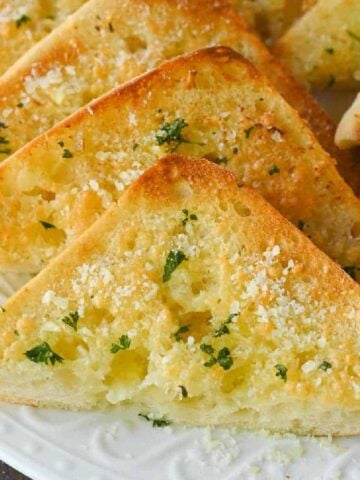 Garlic bread slices on a white plate.