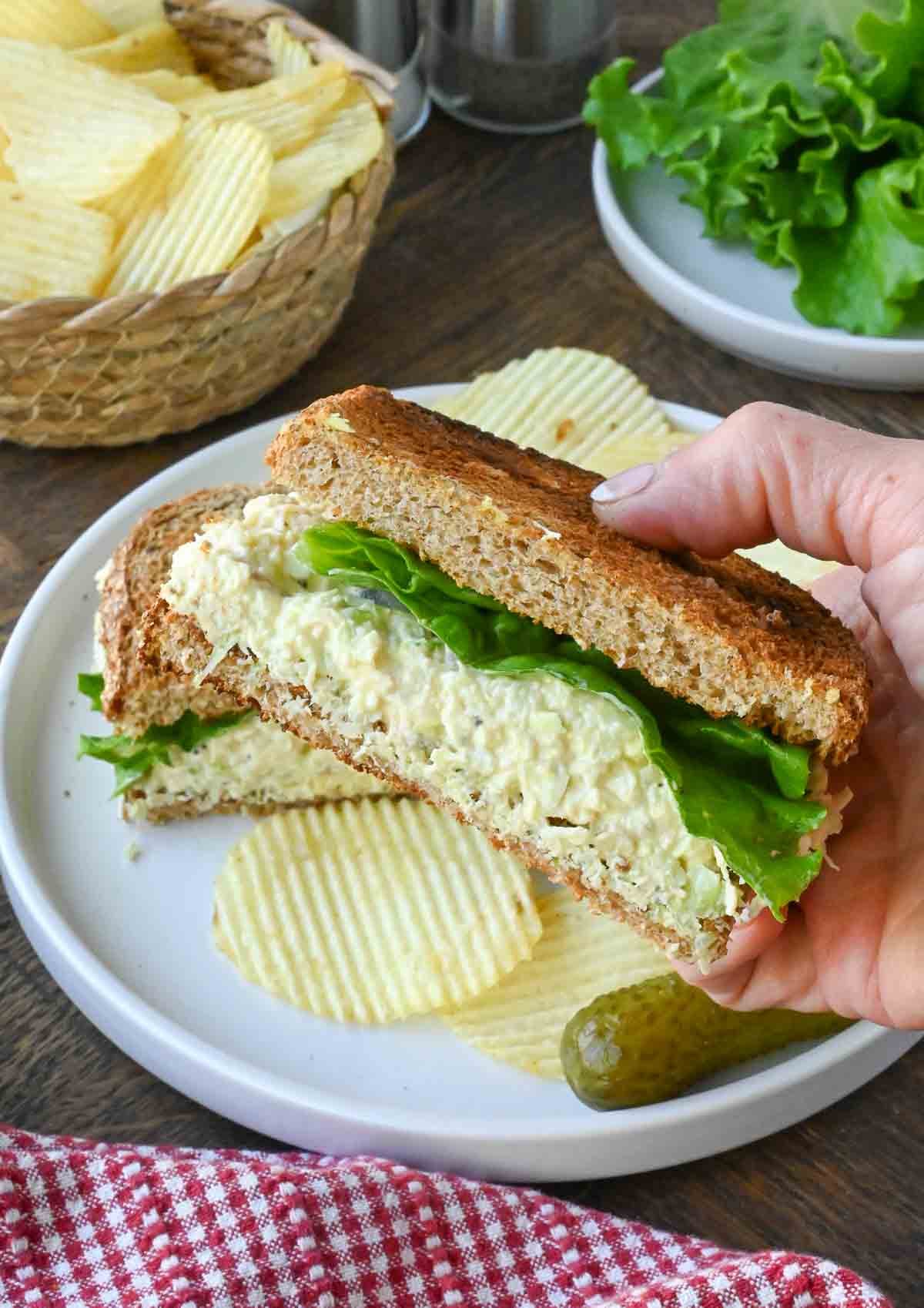 Holding up a half of a copycat chick fil a chicken salad sandwich.