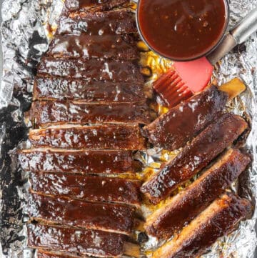 Ribs placed on top of foil with a side of bbq sauce.