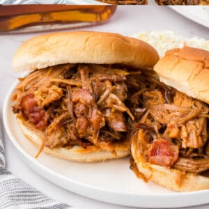 Two bourbon bacon pulled pork sandwiches on a white plate.
