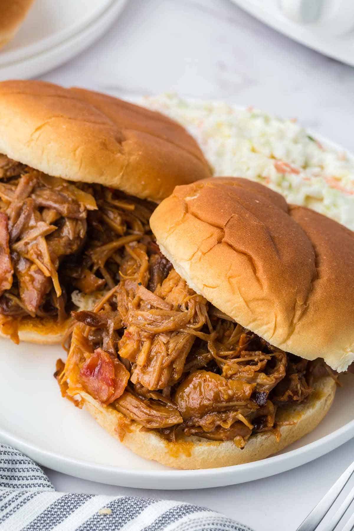 Pulled pork sandwich on a white plate with coleslaw.