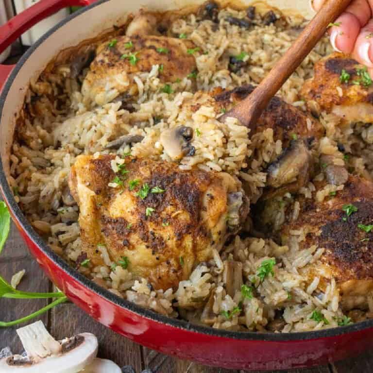 Chicken thighs in a mushroom rice with a spoon scooping some out.