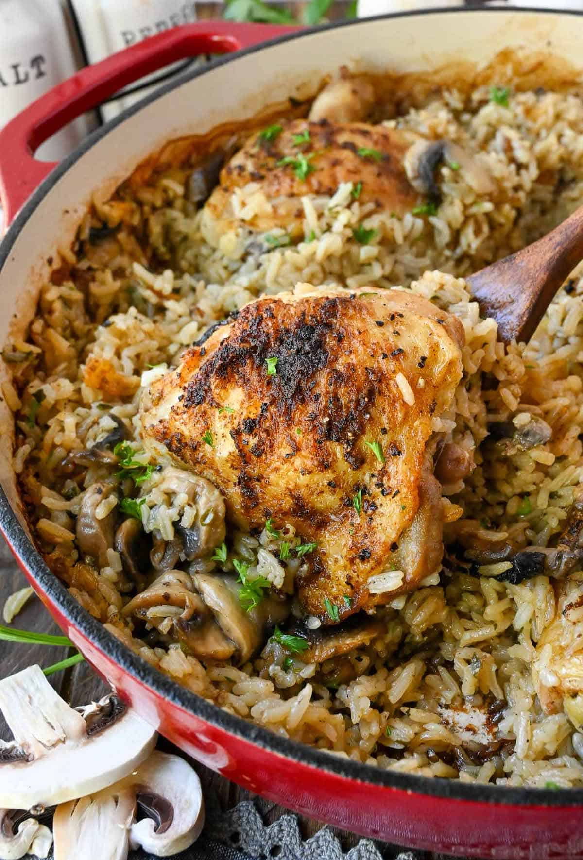 Chicken thighs in a mushroom rice with a spoon scooping some out.