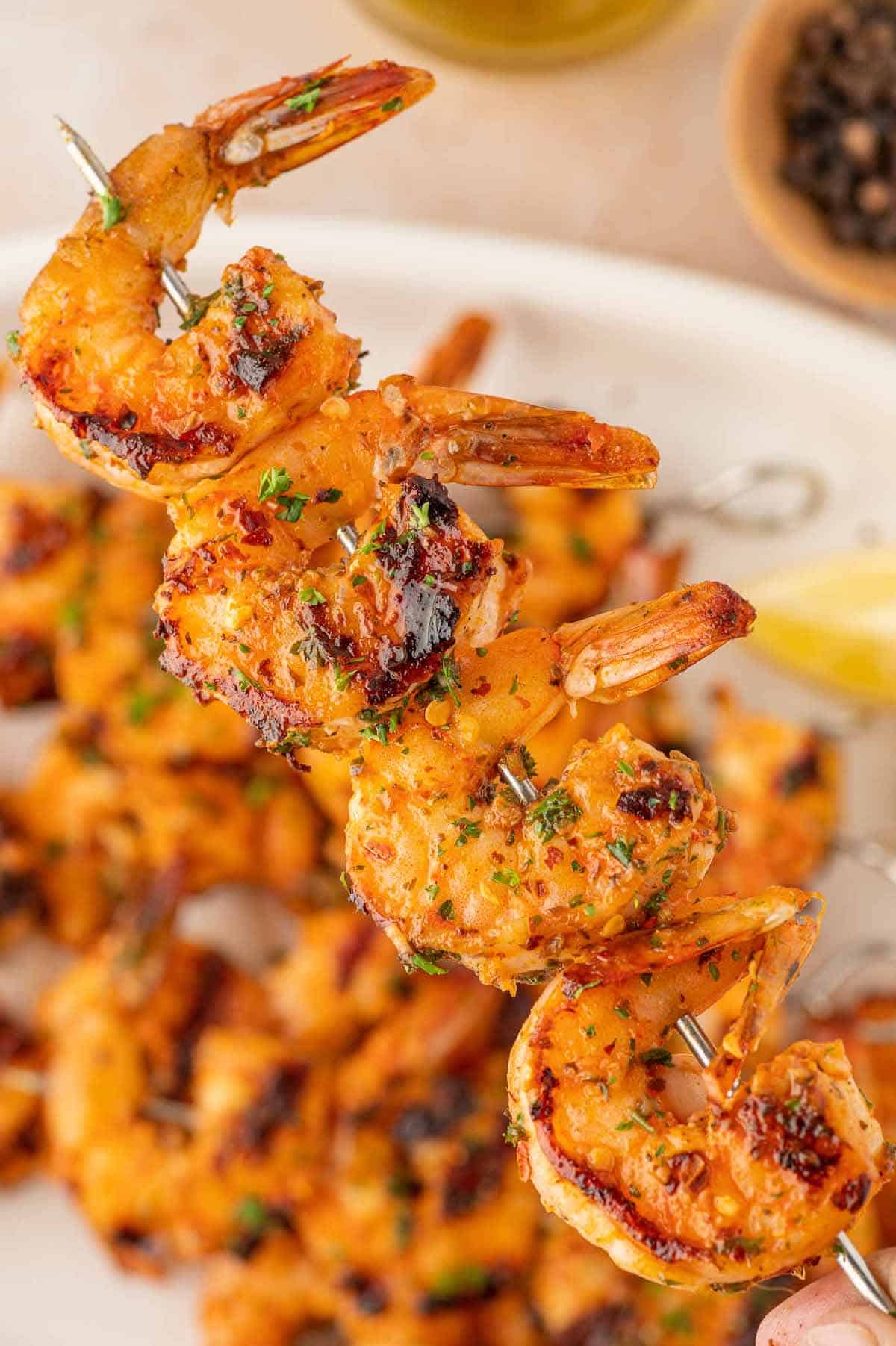 A skewer with grilled shrimp being held.