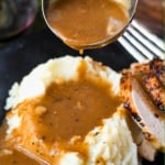 Turkey gravy being poured into mashed potatoes.
