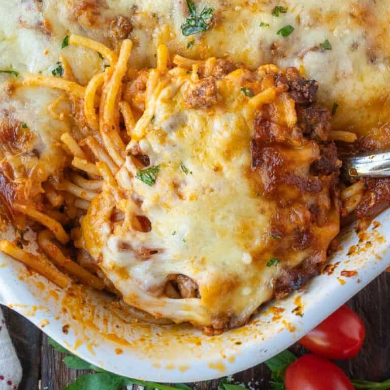 A serving spoon scooping up some baked spaghetti.