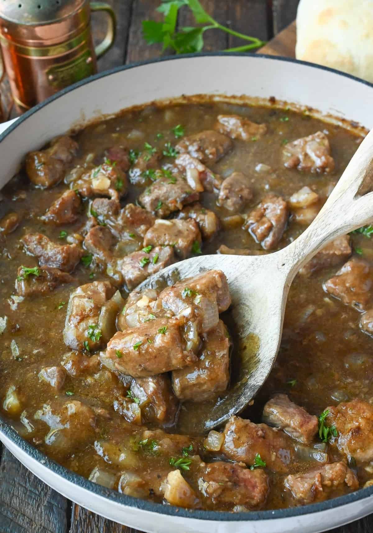 Close up of a spoon in a pot of beef tips and gravy.