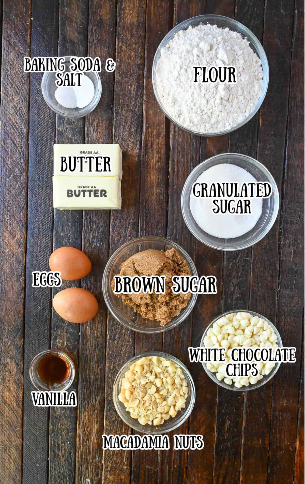 Labelled ingredients for white chocolate macadamia nut cookies on a brown wooden countertop.