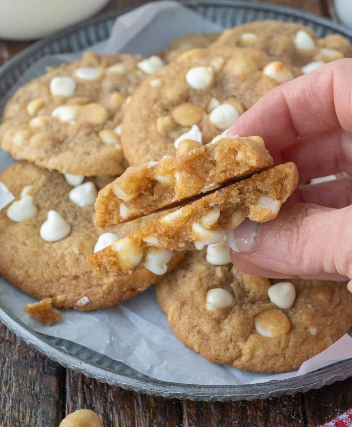 A close up of two halves of a cookie held together with more cookies in the background.