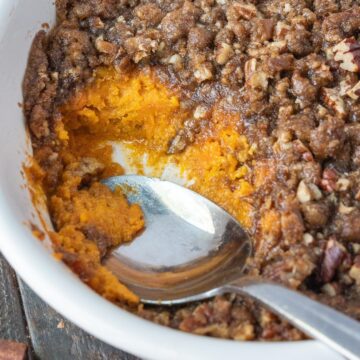 Sweet potato crunch in a casserole dish with a serving missing.