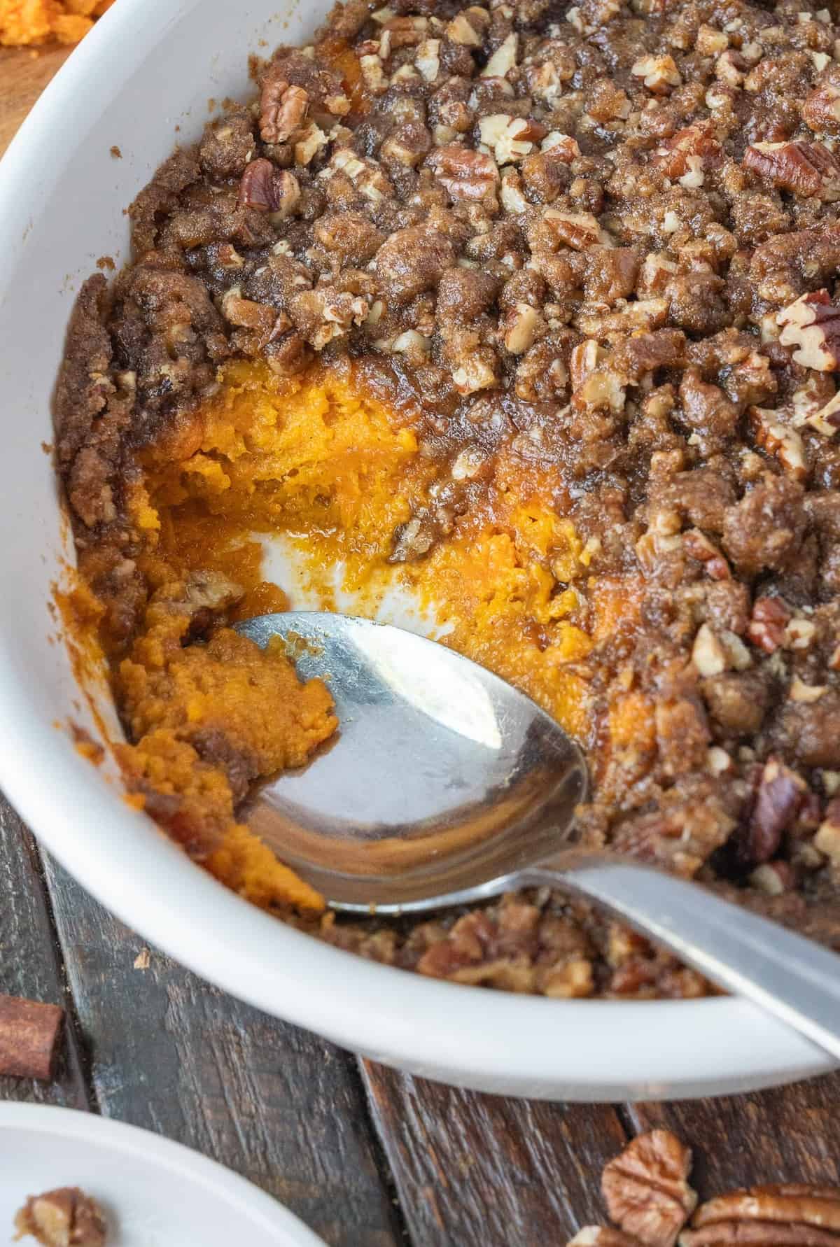 Sweet potato crunch in a casserole dish with a serving missing.