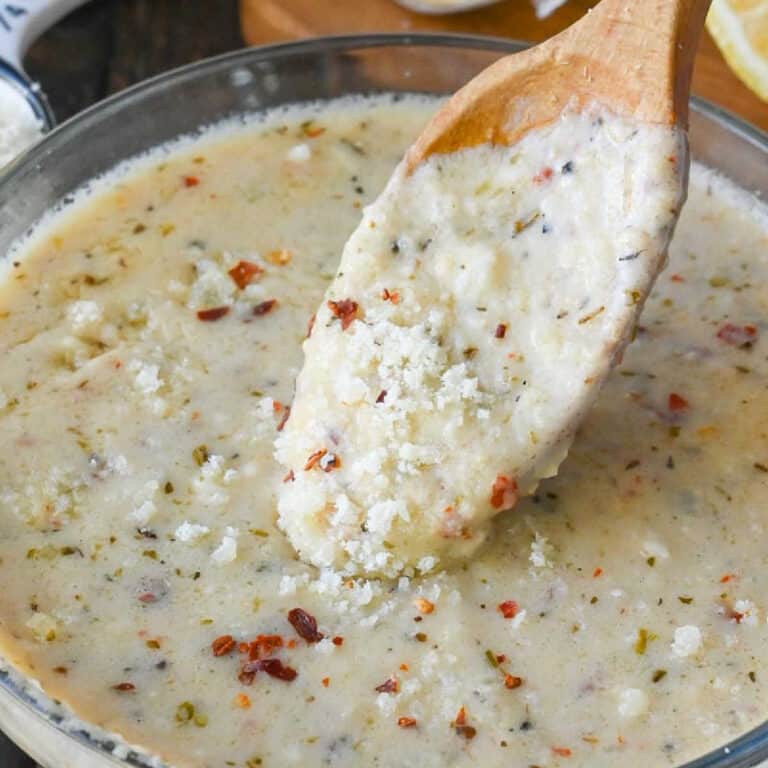 Close up of a spoon stirring garlic parmesan sauce.