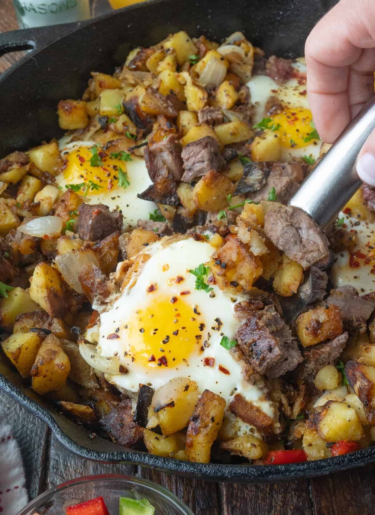 Using a spatula to scoop breakfast hash out of a skillet.