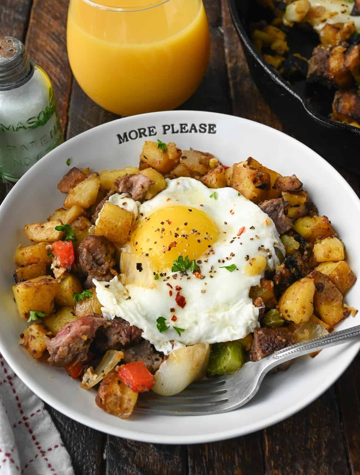 Vertical image of steak and potato breakfast hash in a bowl.
