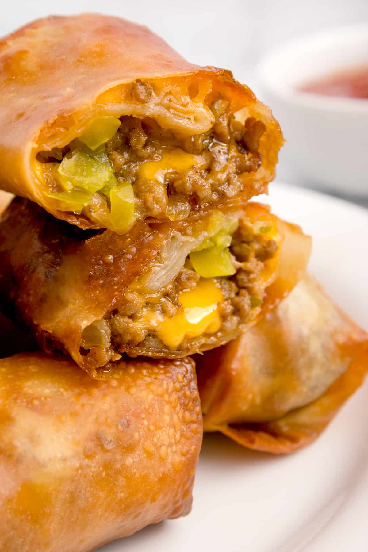Cheeseburger egg roll cut in half and stacked on top of each other.
