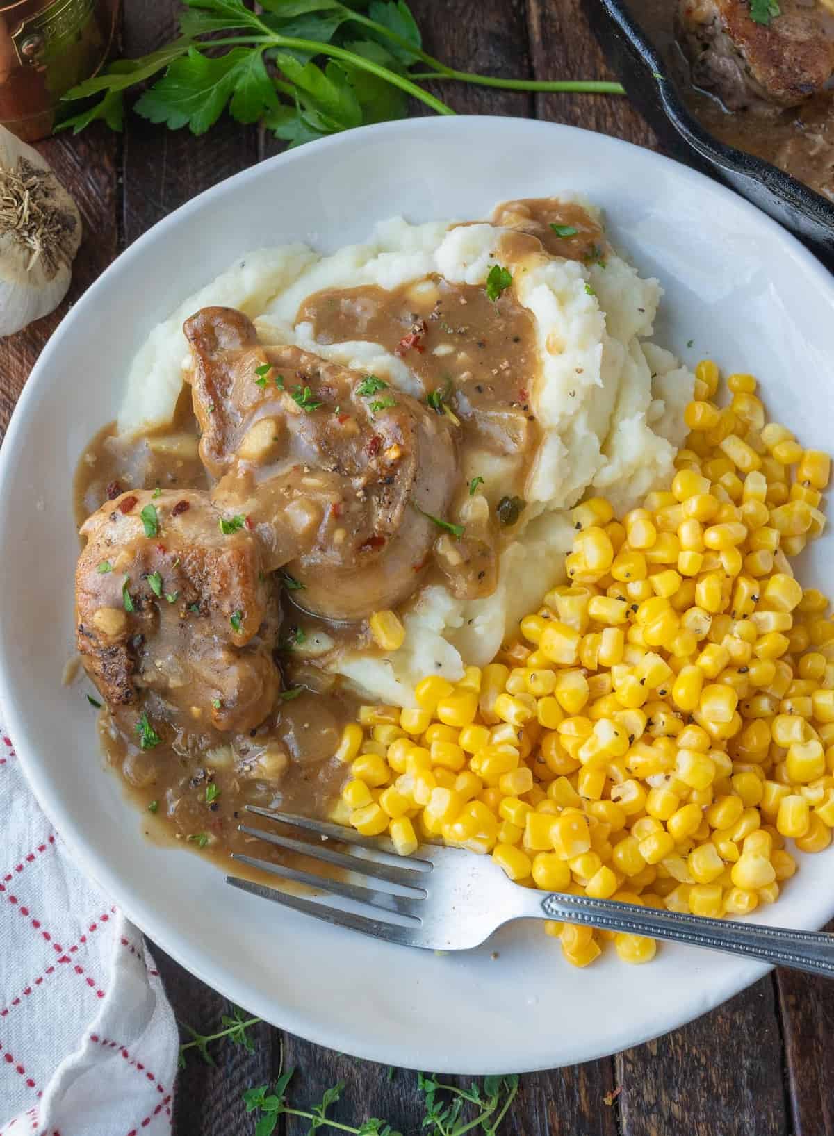 Pork medallions with onion gravy served over mashed potatoes with a side of corn.