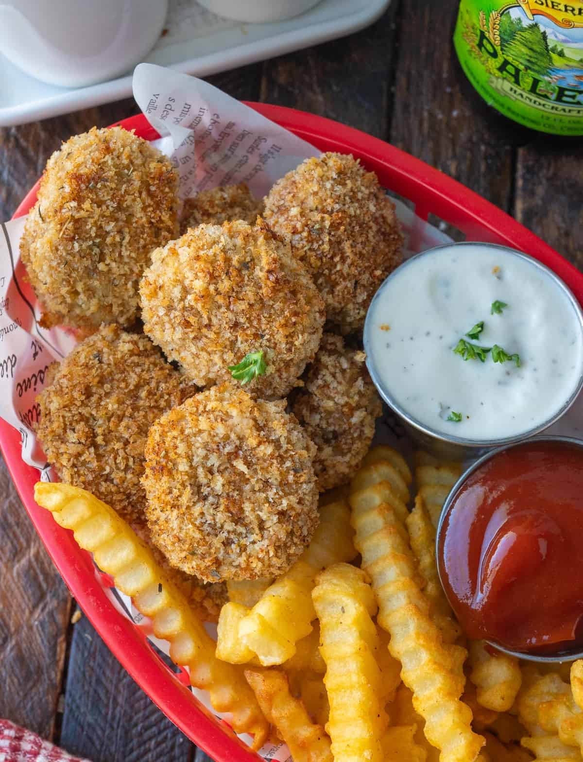 A basket of spicy chicken nuggets with crinkle cut french fries and dipping sauces.