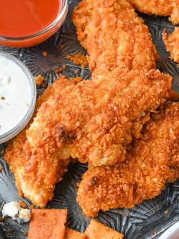 lose up of buffalo chicken tenders with hot sauce and blue cheese dressing.