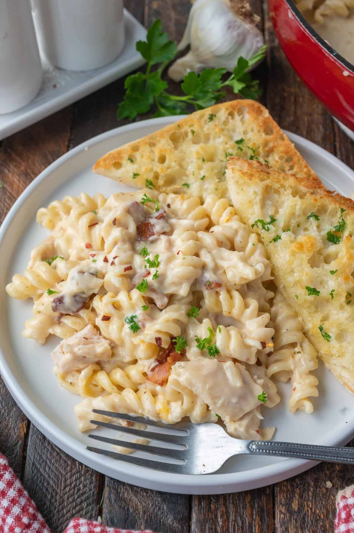 Chicken pasta on a plate with garlic bread.