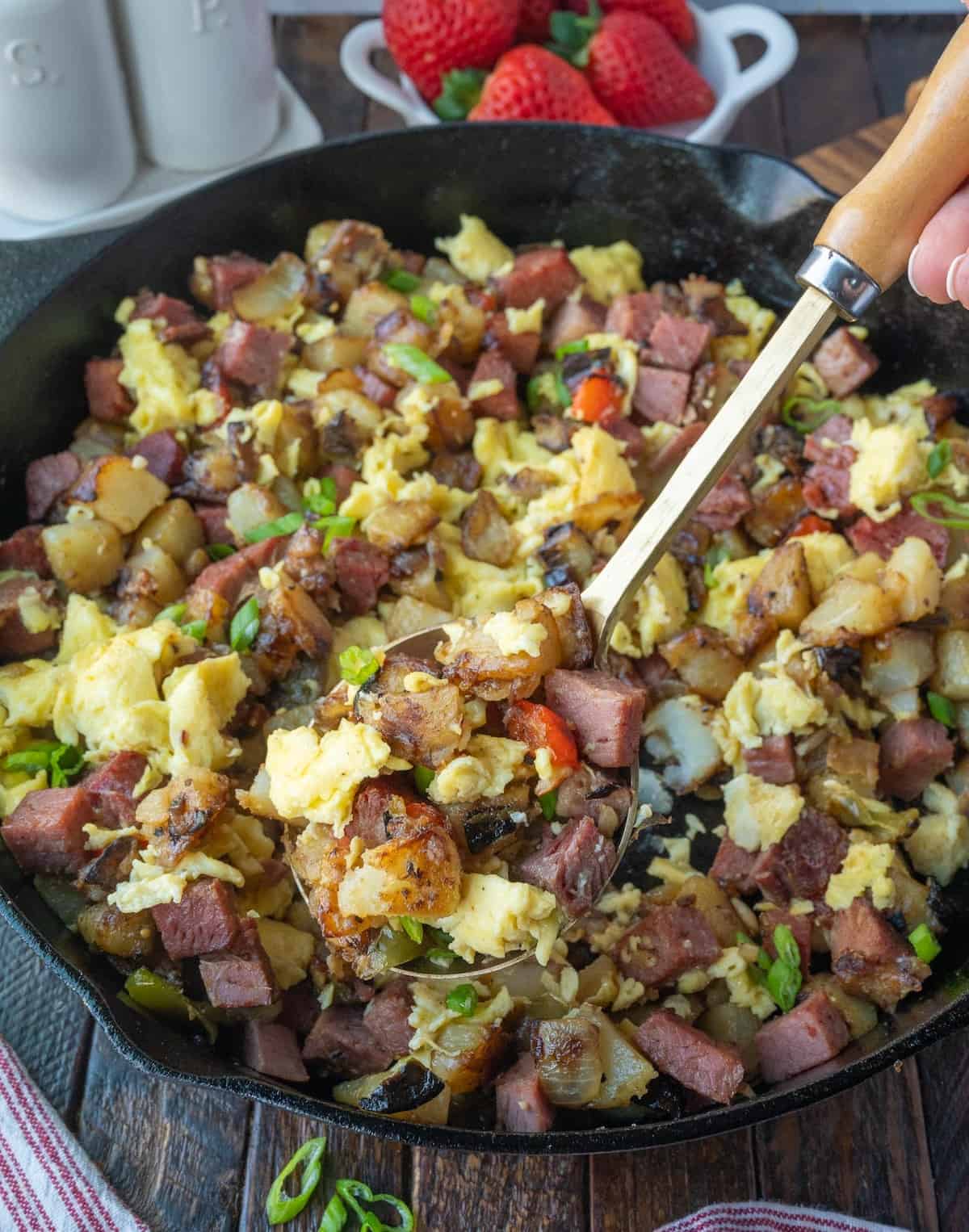 A spoon scooping up some breakfast hash.