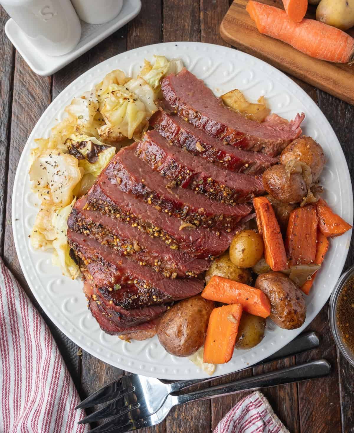 Corned beef slices on a platter with vegetables.