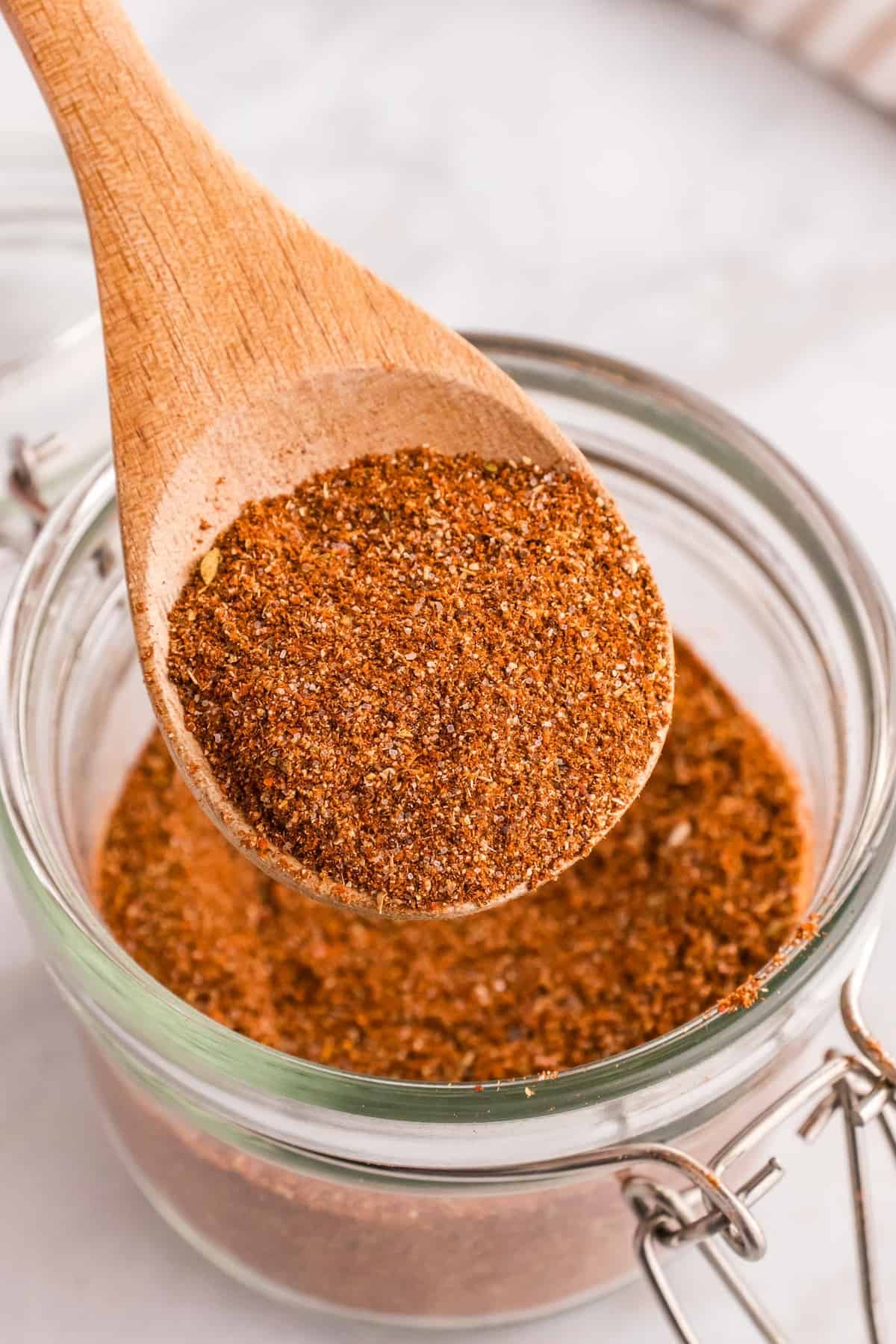 A wooden spoon scooping out some taco seasoning.