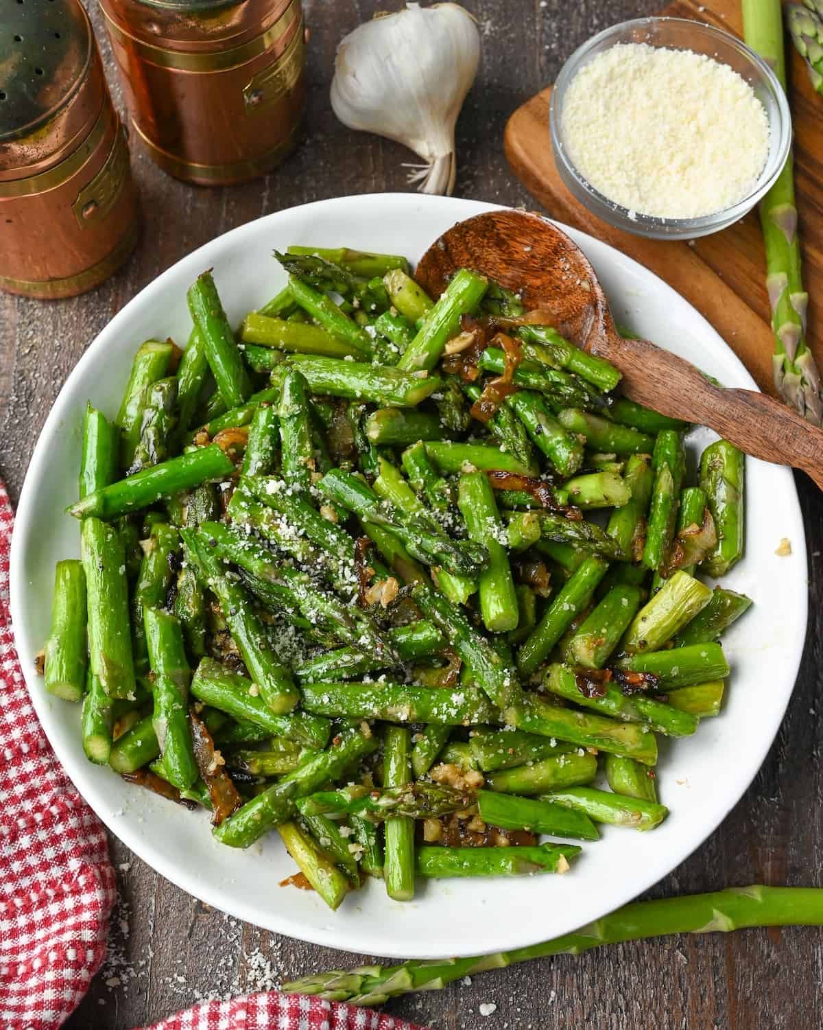 Pan fried asparagus in a white bowl with a spoon.