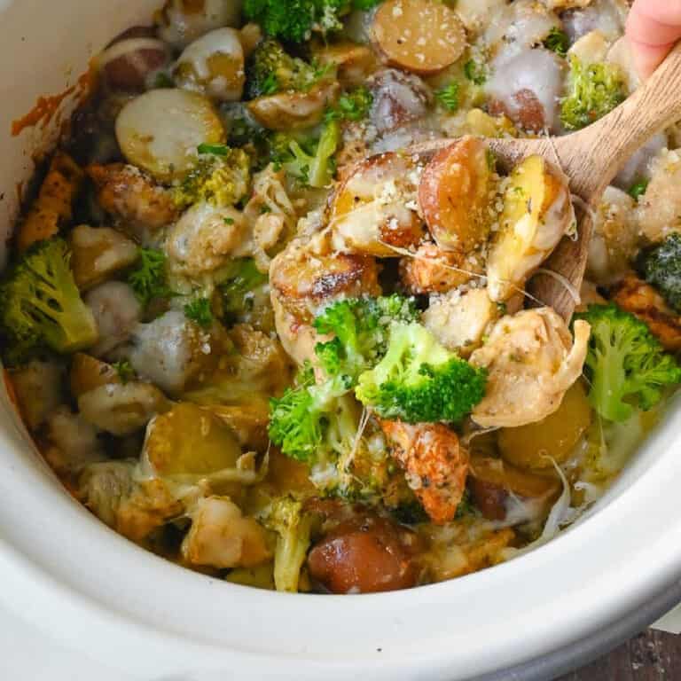 A wooden spoon scooping up some potatoes and chicken.
