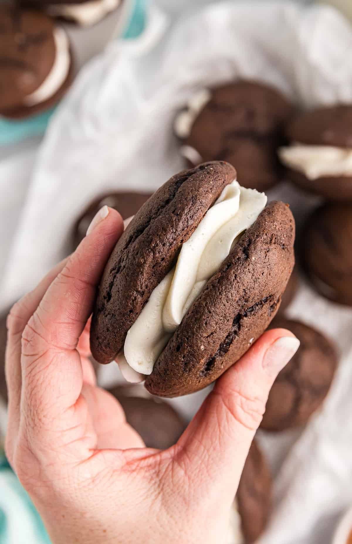 A hand holding a chocolate whoopie pie.