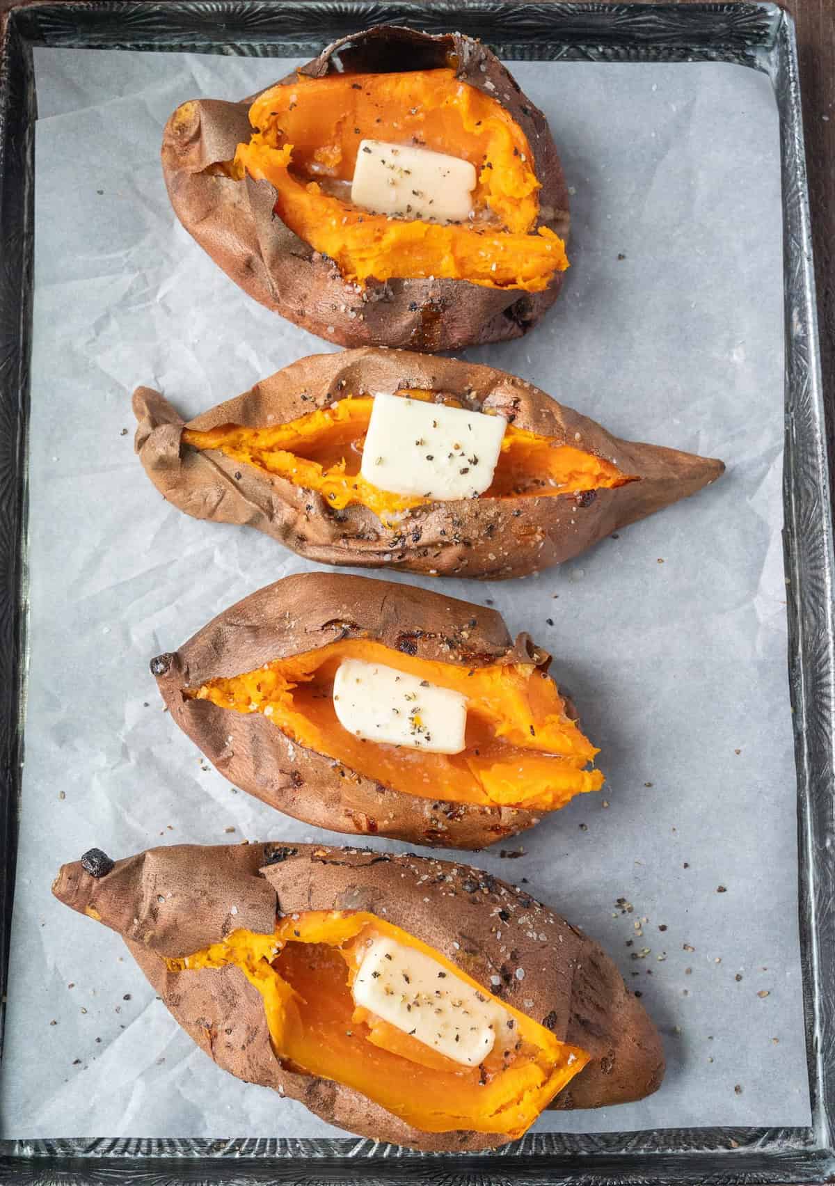 4 air fried sweet potatoes topped with seasoning and a pat of butter.