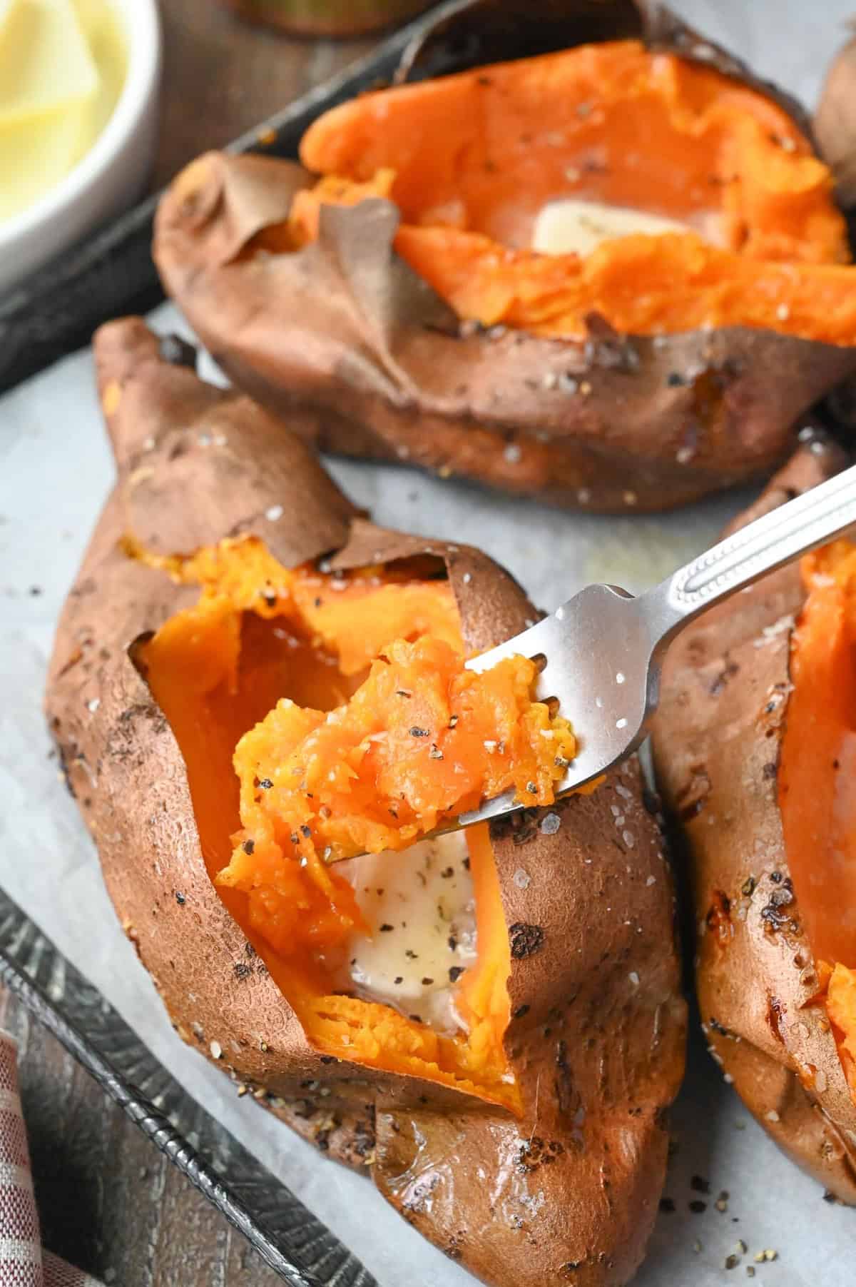 A fork taking a bite of air fryer baked sweet potato.