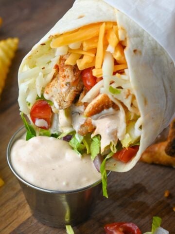 A chicken wrap being dipped into chipotle mayo.