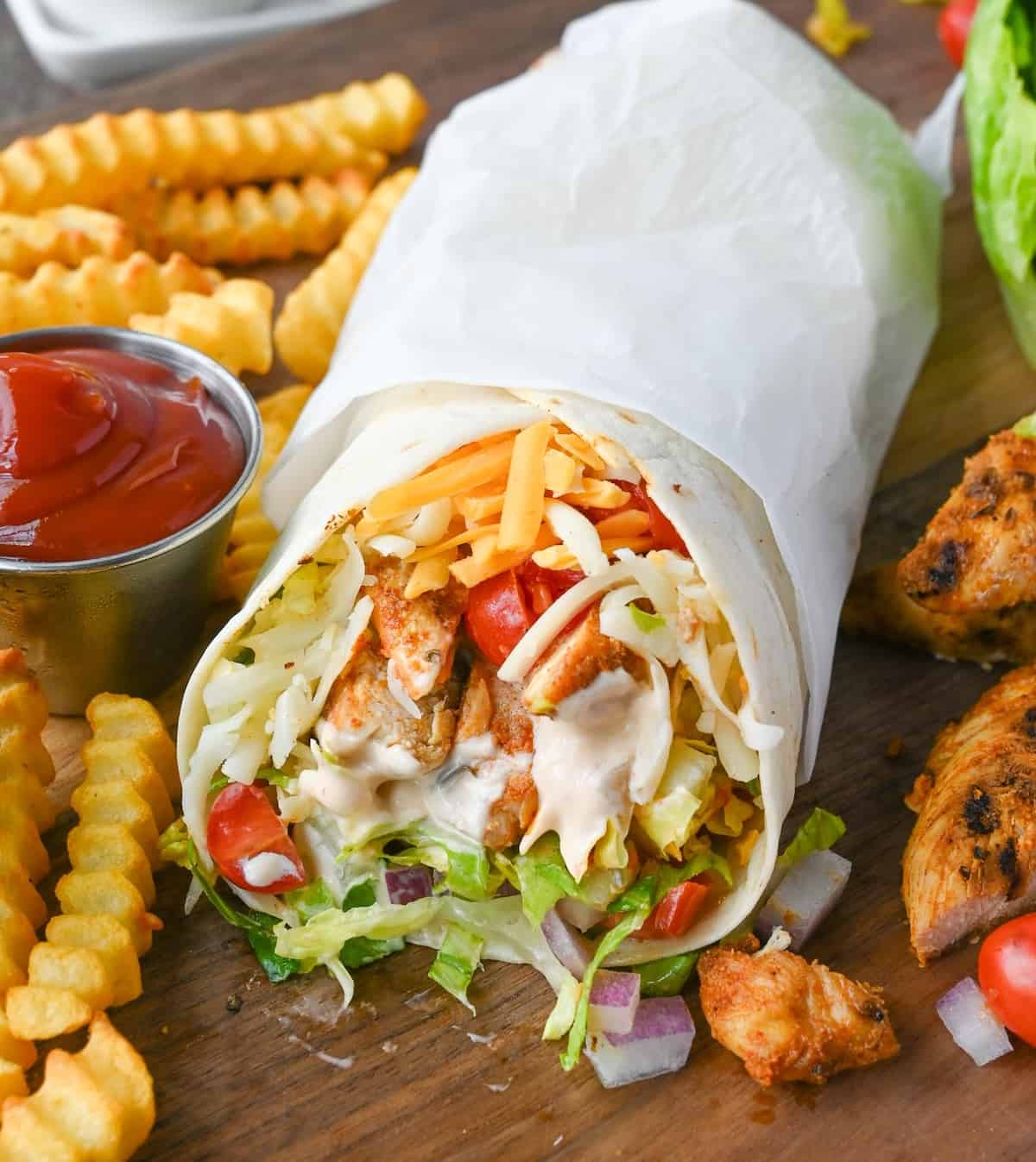 Grilled chicken wrap with a side of fries and ketchup.