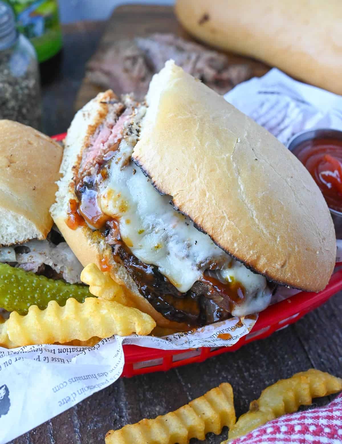 Close up of a grilled tri tip sandwich in a basket with french fries.