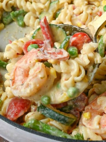 Close up of a spoonful of pasta primavera with shrimp.