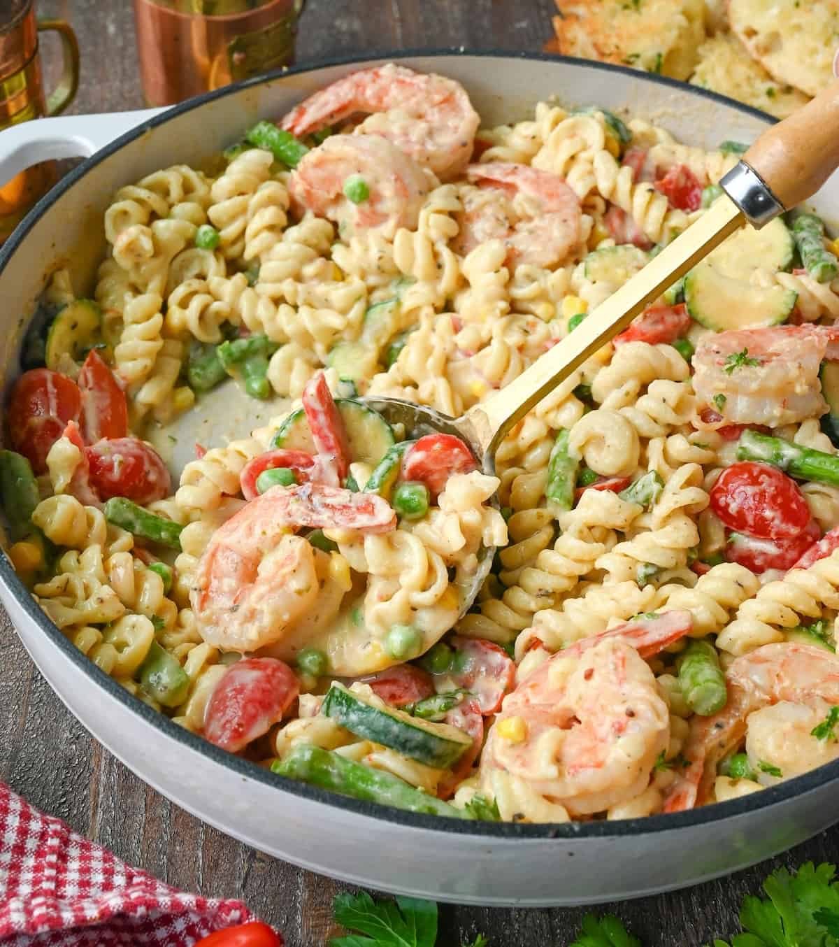 Shrimp pasta primavera in a pot with a metal spoon.