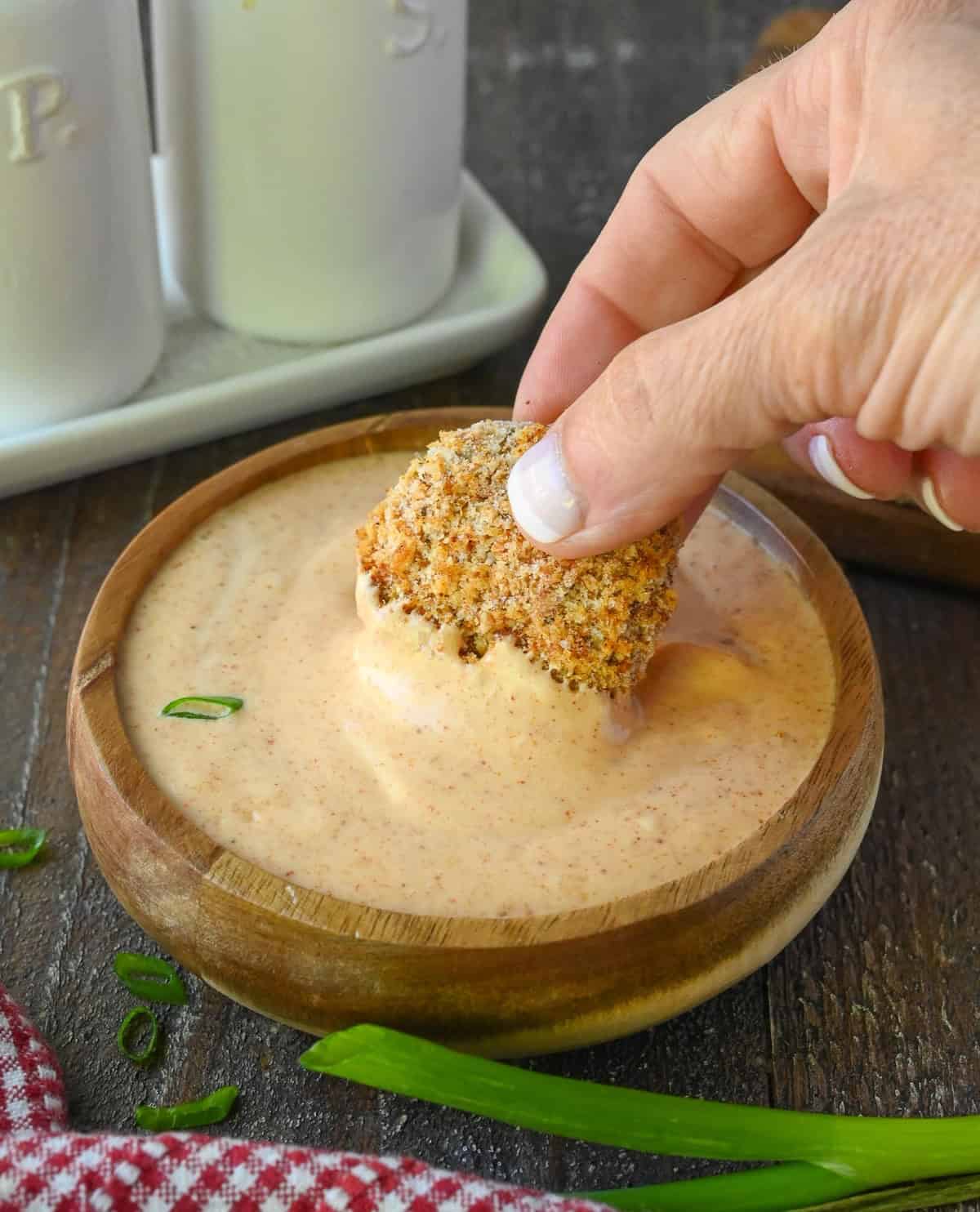 A chicken nugget being dipped into yum yum sauce.