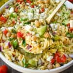 A serving spoon scooping up some chickpea orzo pasta.