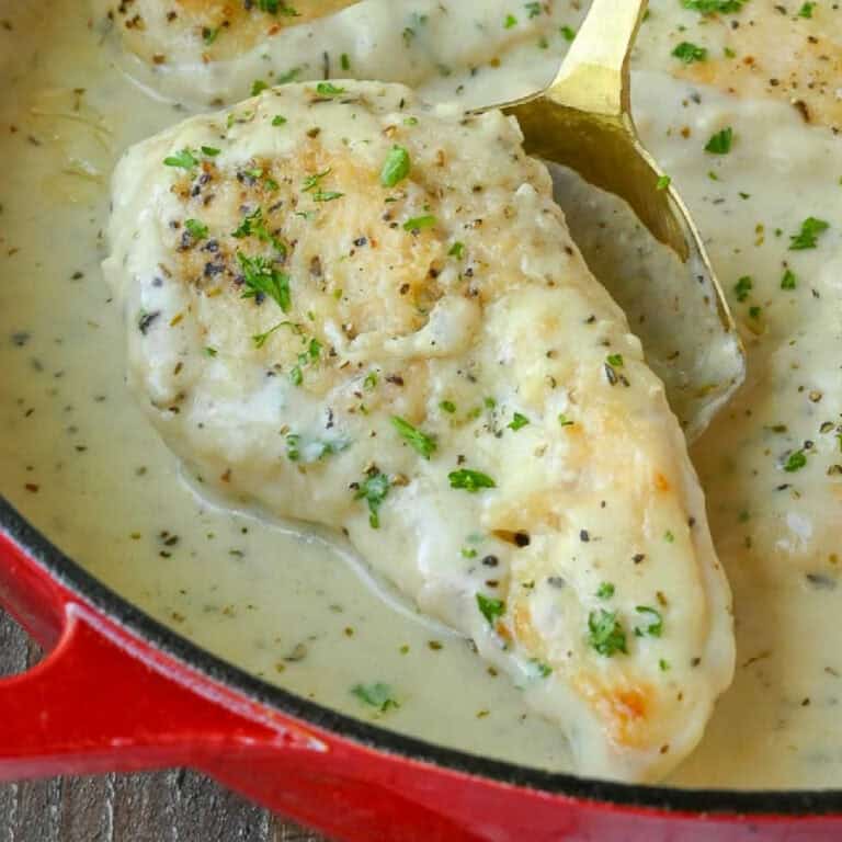 A serving spoon scooping up a chicken breast.