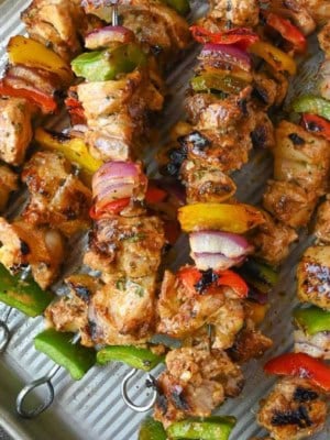 Close up of chicken kebabs on a baking tray.