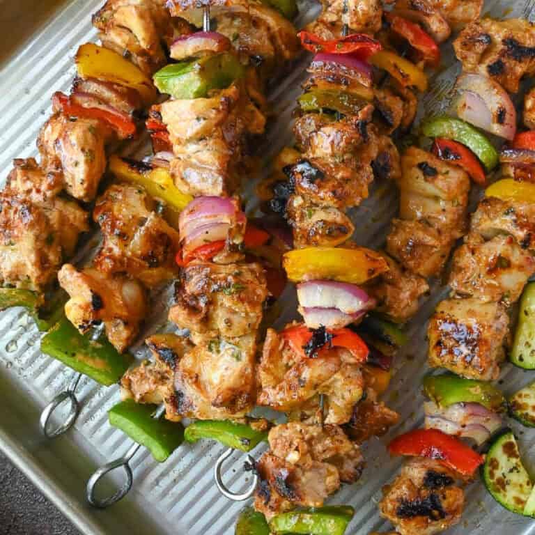 Close up of chicken kebabs on a baking tray.